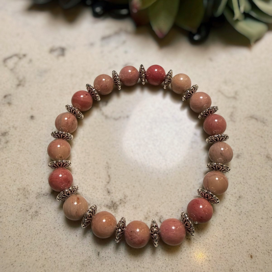 Pink beaded bracelet on a marble surface with succulents in the background