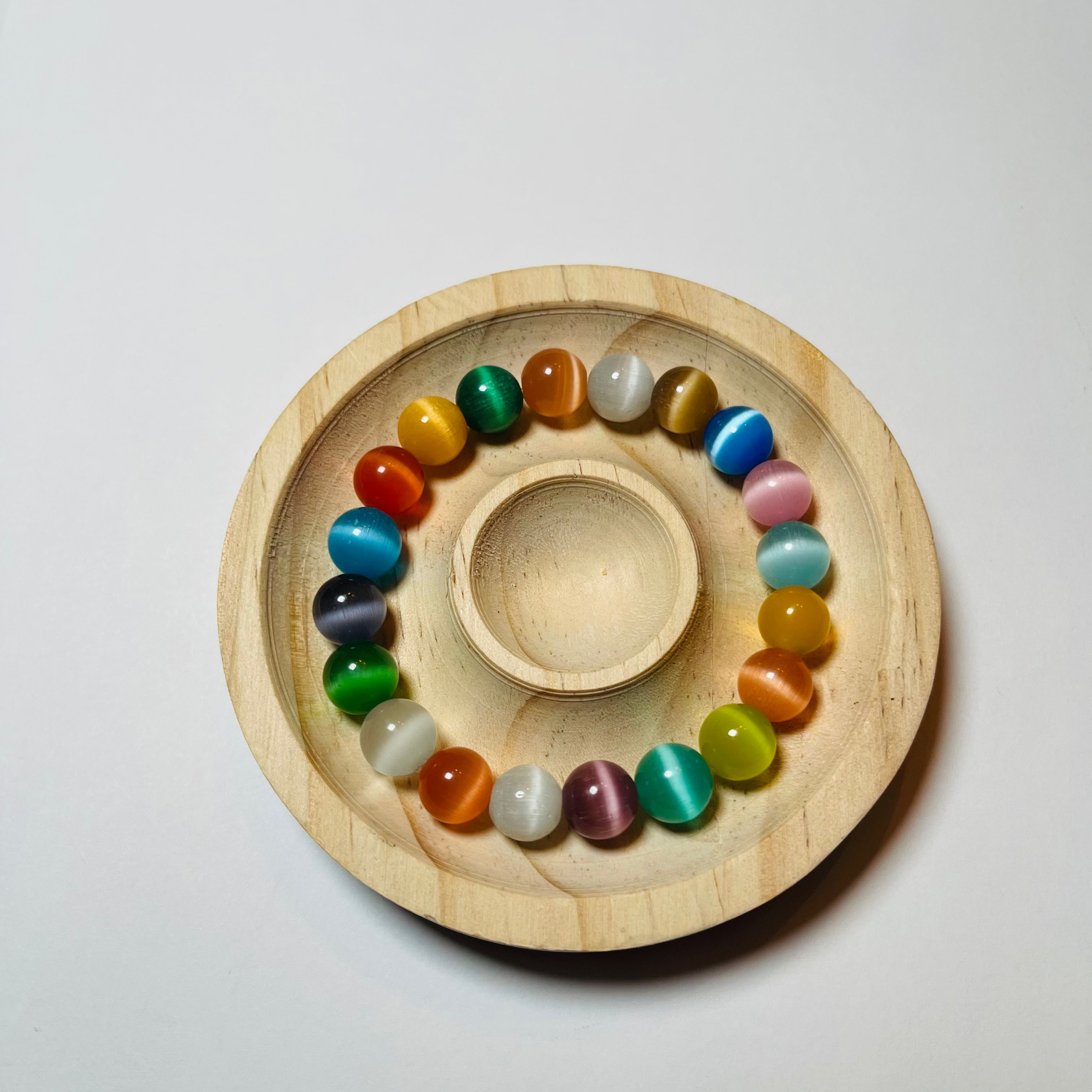 Wooden plate with colorful beads on a white background