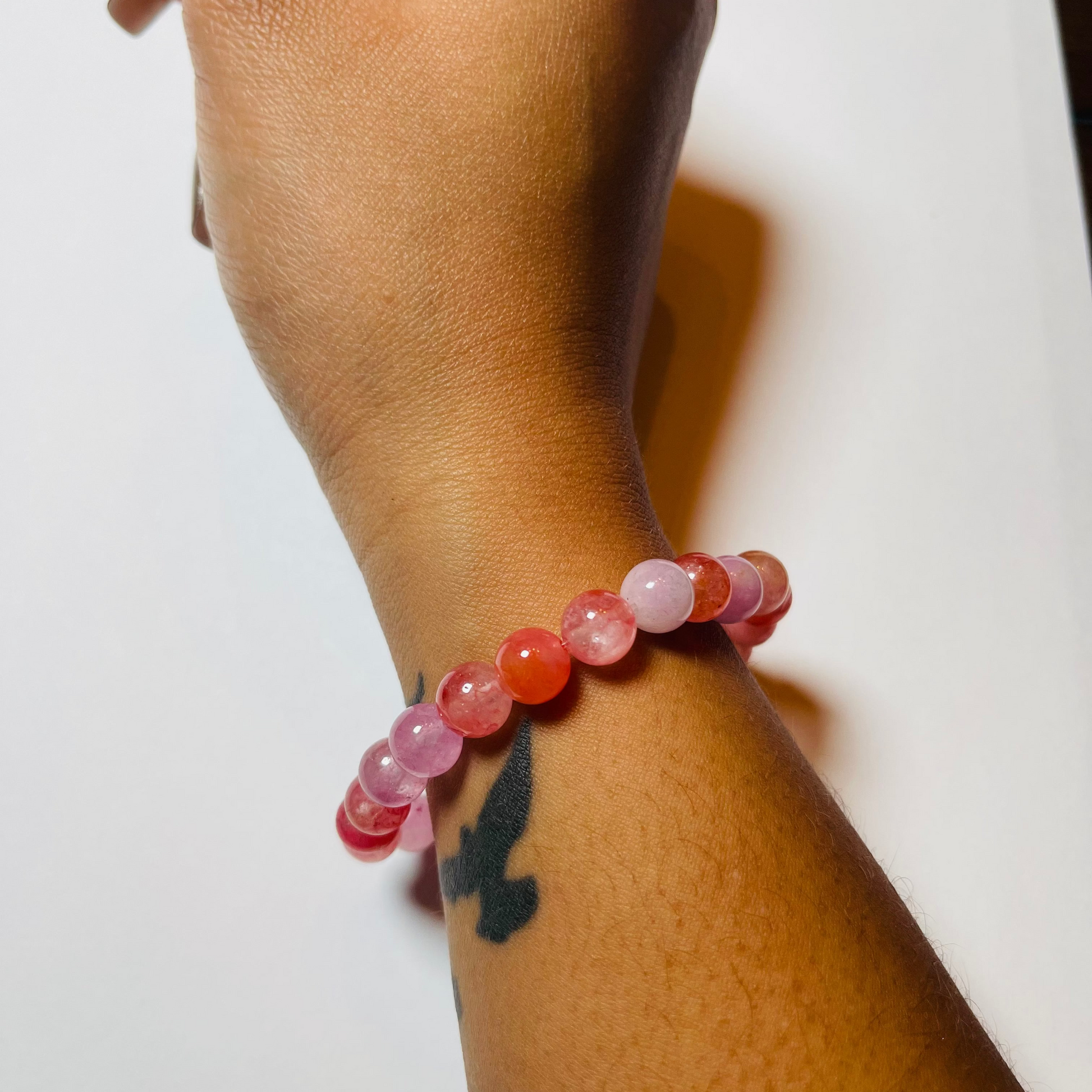 Hand wearing a beaded bracelet on a white background
