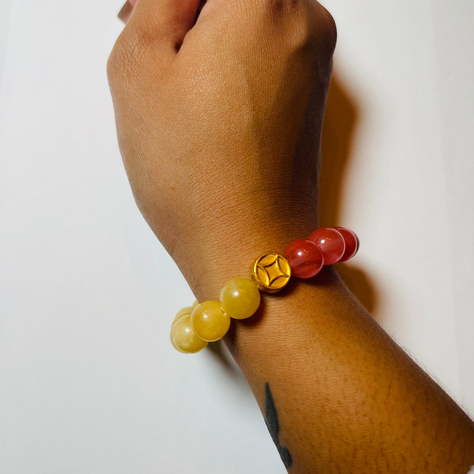 Hand wearing a bracelet with yellow and red beads on a white background