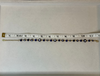 A gold chain bracelet with blue and white evil eye beads, shown on a beige surface with a measuring tape ruler above it for scale.