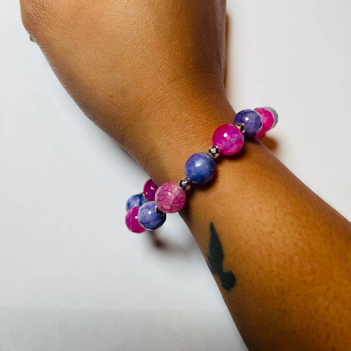 Hand wearing a colorful beaded bracelet on a white background