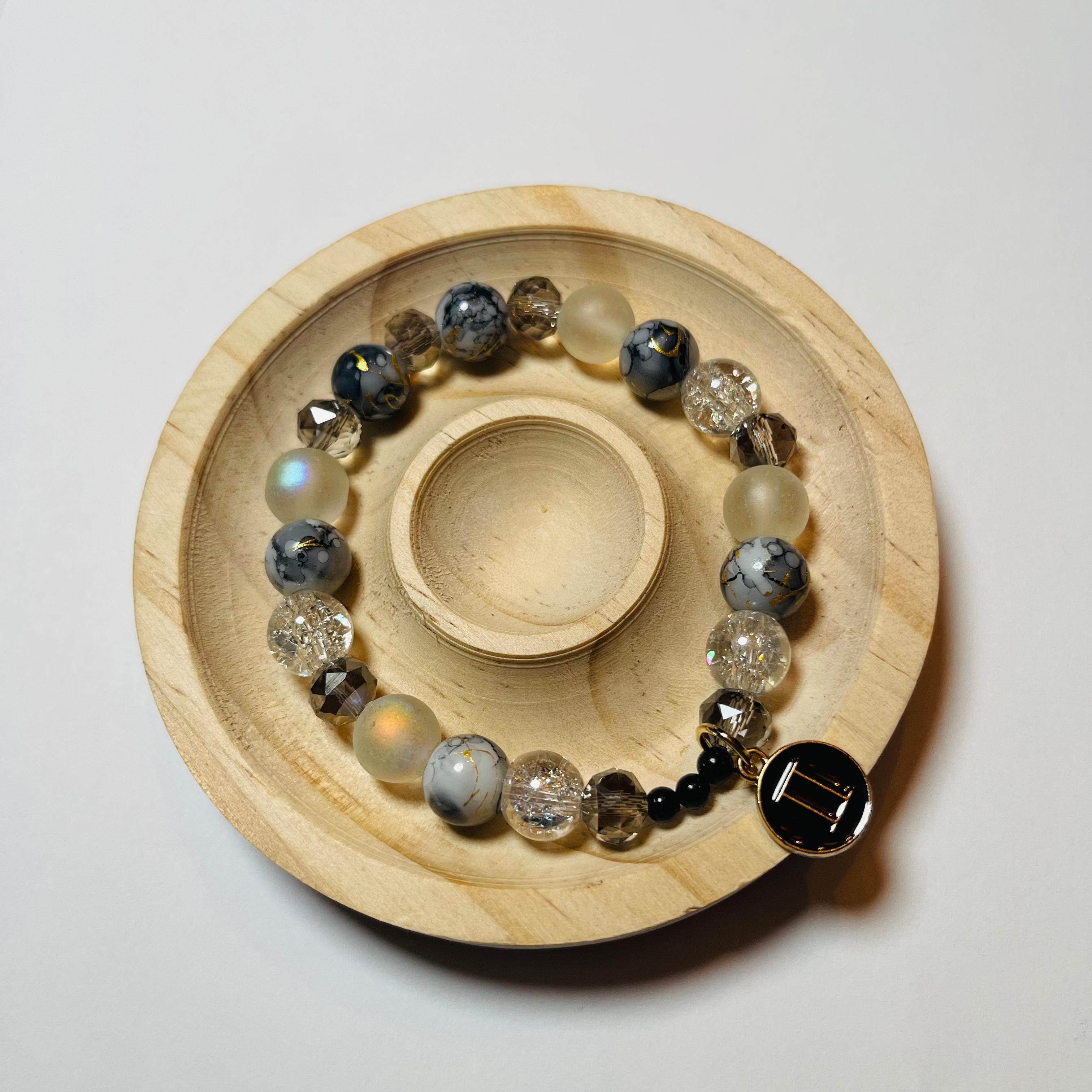 Wooden coaster with a bracelet featuring beads on a white background
