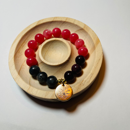 Bracelet with red and black beads on a wooden coaster
