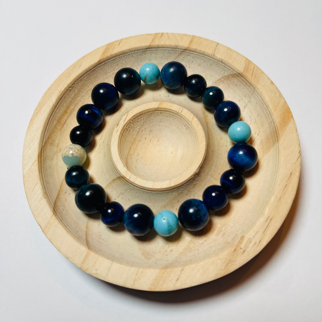 Navy and turquoise beaded bracelet on a wooden stand against a white background