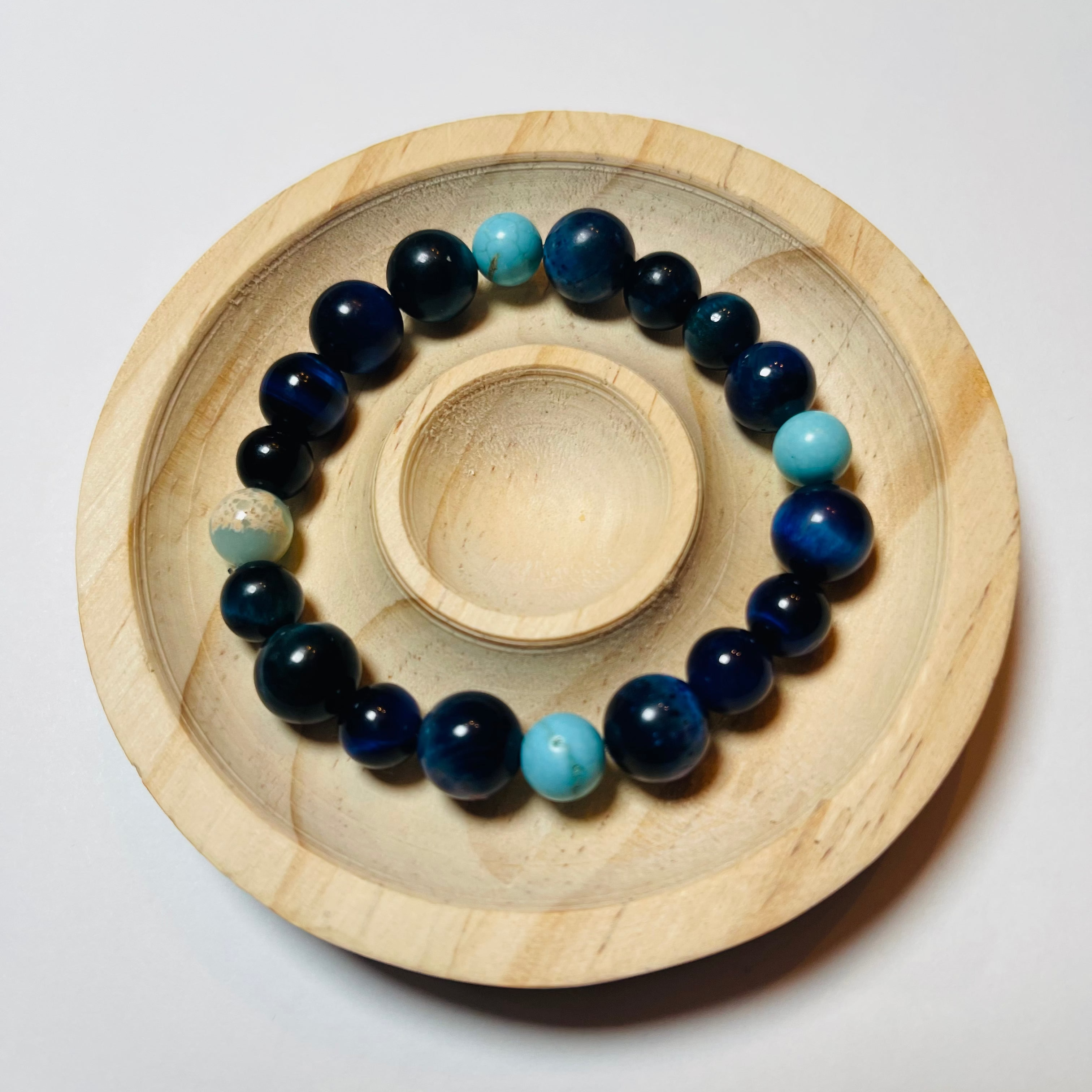 Navy and turquoise beaded bracelet on a wooden stand against a white background