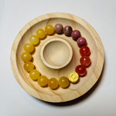Wooden tray with yellow and red beaded bracelets on a white background