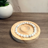 White beaded bracelet on a wooden coaster with a plant in the background