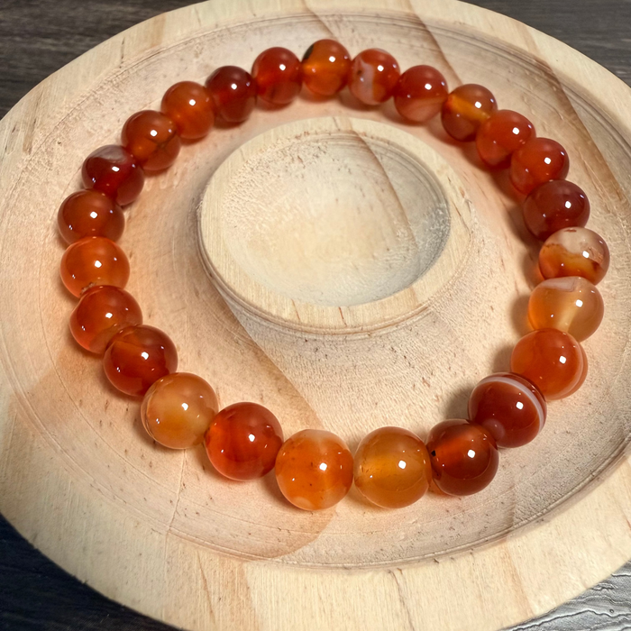 Beaded bracelet with orange and red stones on a wooden surface