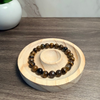 Beaded bracelet on a wooden stand with a plant in the background