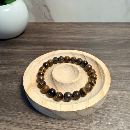 Beaded bracelet on a wooden stand with a plant in the background