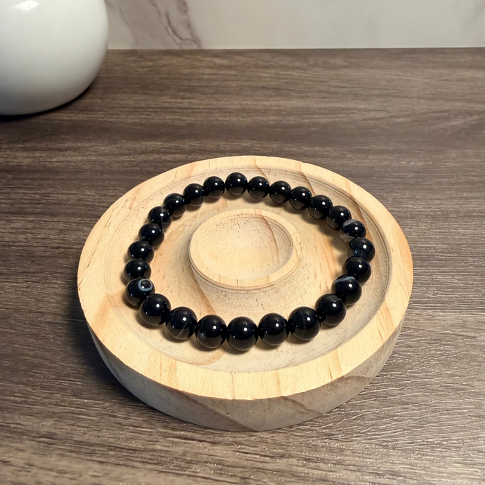 Black beaded bracelet on a wooden stand with a blurred background
