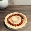 Red jasper beaded bracelet on a wooden stand with a blurred background