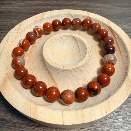 Red jasper Beaded bracelet on a wooden and stone surface