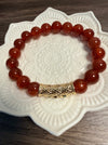 Carnelian beaded bracelet with a gold clasp on a decorative white plate.