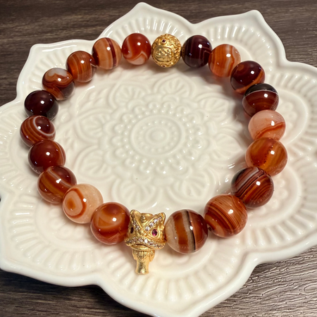 Bracelet with brown and gold beads on a decorative white plate