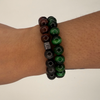Bracelet with green and black beads on a wrist against a white background